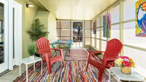 A covered patio area with red chairs, a small table, a potted plant, and colorful artwork on the walls. - Close to Sedona, Cottonwood, Wineries & Jerome (Cottonwood)