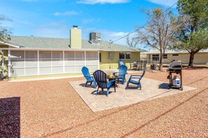 A backyard with a patio, blue chairs, a grill, and a covered garage.