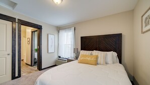 A bedroom with a large bed, a wooden headboard, a bedside table with a lamp, and a door leading to another room. - Lovely 3 bedroom Apartment in Bozeman! Unit #C  (Bozeman)
