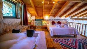 Eine Holzhütte mit einem großen Bett, einem kleineren Bett, einer Badewanne und einer Sitzbank.