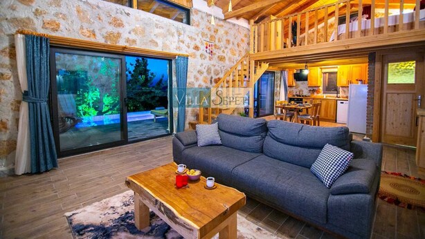 Ein gemütliches Interieur mit Sofa, Holztisch und Balkon mit Blick auf Bäume.