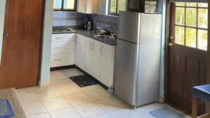 A kitchen with wooden ceiling beams, a refrigerator, a microwave, and a sink. - Blue Villa Aruba (Oranjestad)
