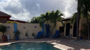A swimming pool with clear water, surrounded by a tiled deck and potted plants. - Blue Villa Aruba (Oranjestad)