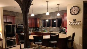 Una cocina moderna con una isla central, taburetes de bar e iluminación colgante.