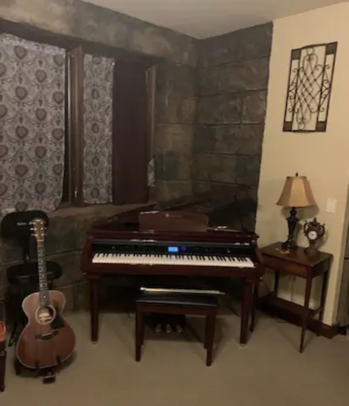 Um quarto com um piano, uma guitarra e um abajur.