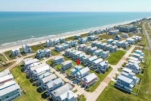 Una zona residencial costera con varias casas de dos pisos, una playa y una calle.