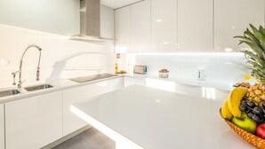 A modern kitchen with white cabinetry, stainless steel appliances, and a central island.