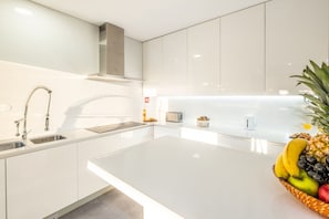 A modern kitchen with white cabinetry, stainless steel appliances, and a central island.