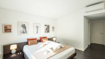 A hotel room with a bed, bedside tables, a nightstand, and wall-mounted artwork.