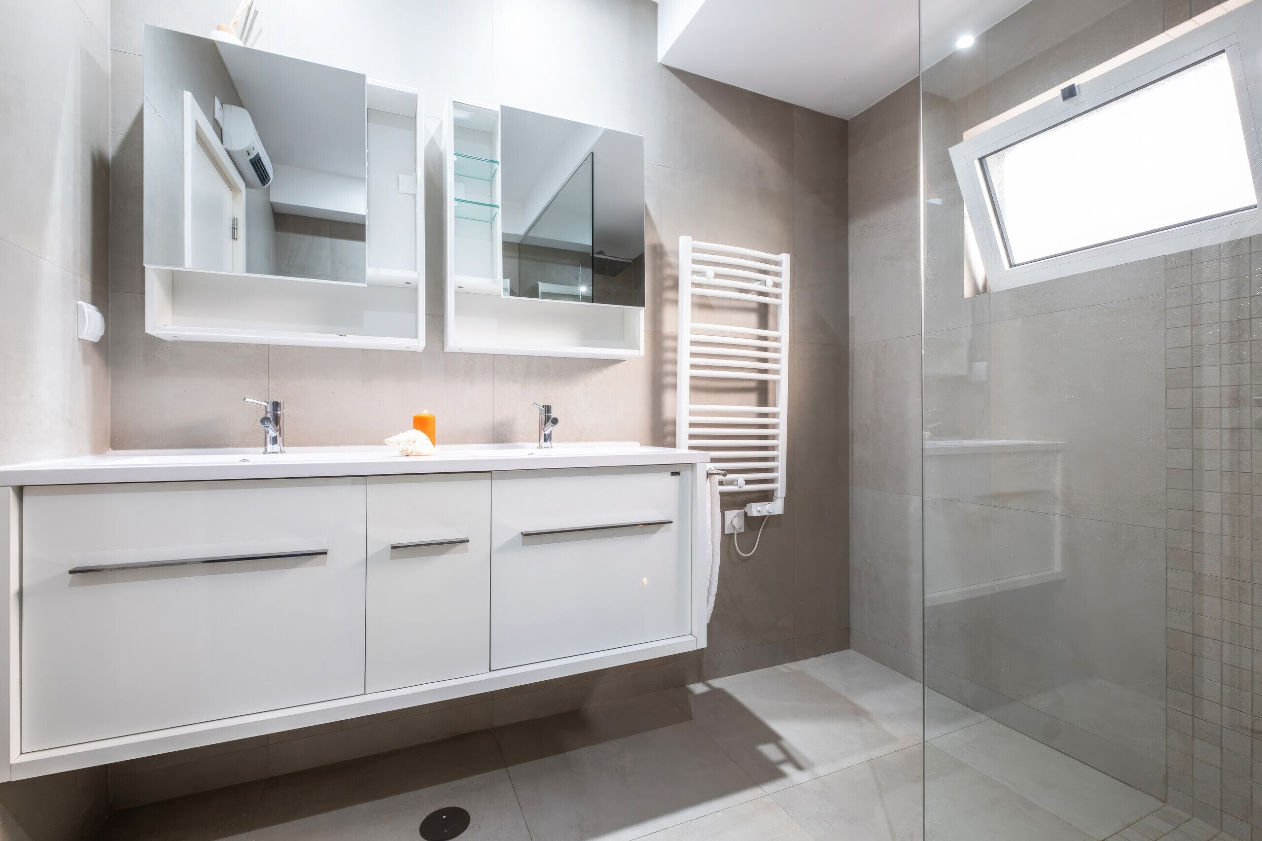 A modern bathroom with a white vanity, a glass shower enclosure, and a built-in towel rack.