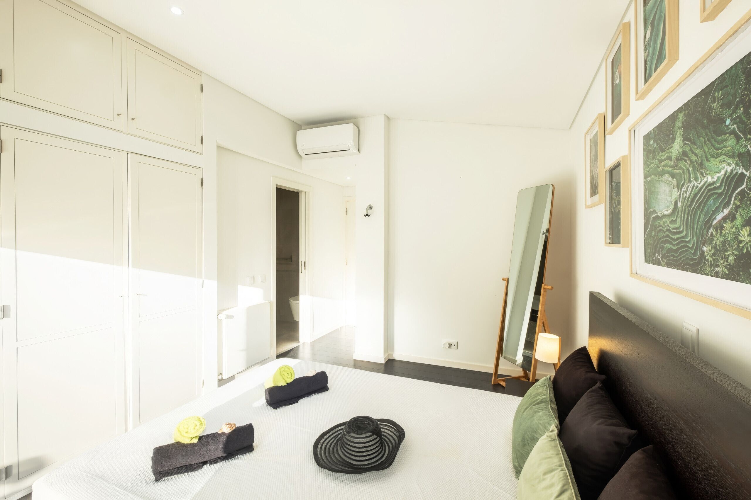 Une chambre d’hôtel avec un lit, une armoire, une salle de bain et un grand miroir.