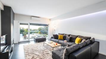Ein modernes Wohnzimmer mit Sofa, Couchtisch und Flachbildfernseher.