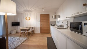 Eine moderne Küche mit weißen Schränken, einer Mikrowelle und einer Holztür.
