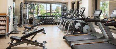A gym with treadmills, dumbbells, and weight machines.
