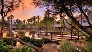 A resort with a wooden bridge, palm trees, and a view of the buildings in the background. - The Westin Mission Hills Resort Villas, Palm Springs (Rancho Mirage)