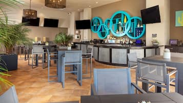 A modern bar area with a curved counter, multiple seating options, and a large screen mounted on the wall.