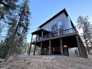 Une cabane à deux étages dotée d’un balcon, entourée d’arbres.