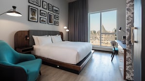 Ett modernt hotellrum med en stor säng, ett skrivbord och utsikt över staden.