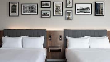 Habitación de hotel con dos camas, cabecero de madera y una pared decorada con fotografías enmarcadas.
