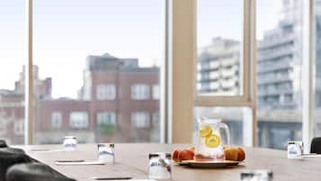 A conference table with a pitcher of iced tea, a plate with fruit, and salt and pepper shakers.
