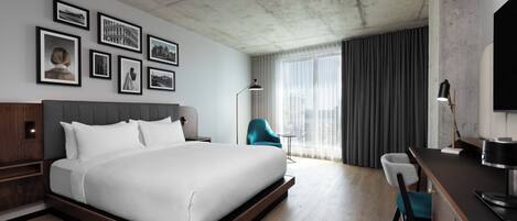 A modern hotel room with a large bed, a desk, a chair, and a television.