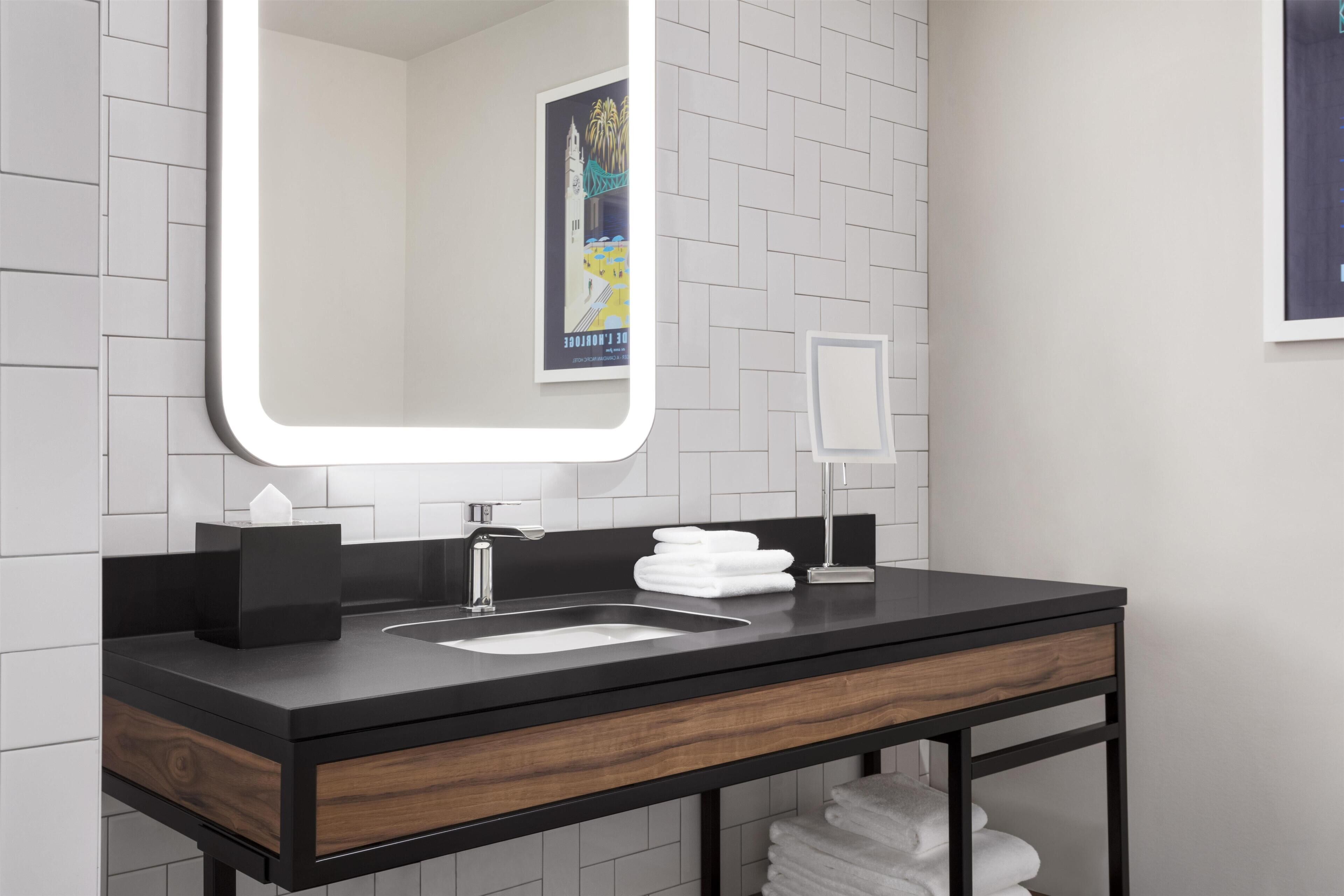 Un bagno moderno con un piano di lavoro nero, uno specchio, un lavandino e un porta asciugamani.