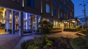 Ett Hyatt Centric-hotell med ett väl upplyst utomhusområde med sittplatser och en vacker trädgård.