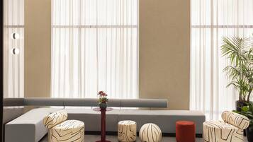 A modern living room with a sofa, ottomans, a small table with a vase, and a potted plant.