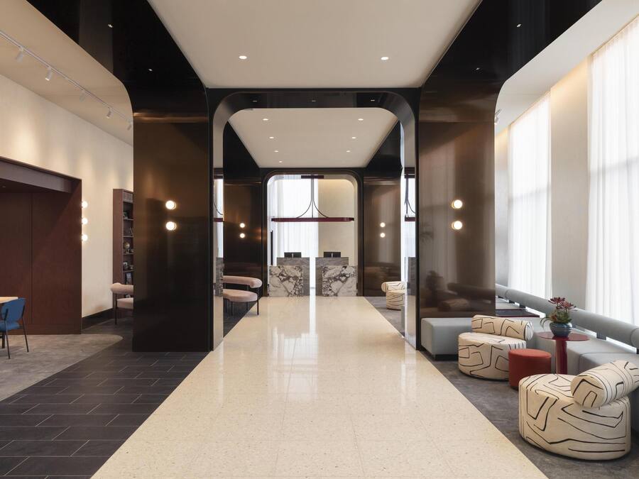 Un moderno vestíbulo de hotel con una recepción central, zonas de estar y vistas al exterior.