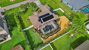 Vista aérea de una propiedad residencial con techo de paneles solares, piscina y jardín bien cuidado.