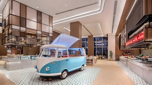 A retro-themed van displayed in a modern interior with a checkered floor, wooden paneling, and a large window. - Holiday Inn Hotel & Sts Wuhan International Expo (Wuhan)