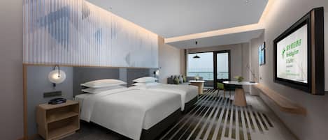 A modern hotel room with two beds, a desk, a chair, a TV, and a view of the city.
