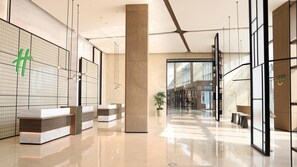 A modern lobby with a reception desk, a large pillar, and a view into the lounge area. - Holiday Inn Hotel & Sts Wuhan International Expo (Wuhan)