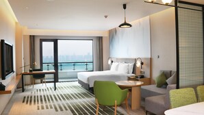 Habitación de hotel con cama, escritorio, silla, sofá y vista a la ciudad.
