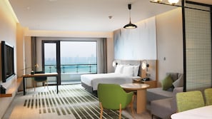 A hotel room with a bed, a desk, a chair, a sofa, and a view of the city. - Holiday Inn Hotel & Sts Wuhan International Expo (Wuhan)