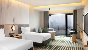 Een hotelkamer met twee bedden, een bank, een tafeltje en een balkon met uitzicht over de stad.
