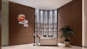 Ein moderner Empfangsbereich mit einer Holzvertäfelung, einem Empfangstresen, einem Blumentopf und einem Logo mit 'Hi Bowl' und chinesischen Schriftzeichen.