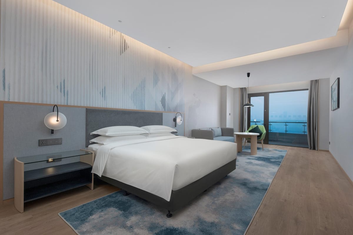 Habitación de hotel moderna con una cama grande, un escritorio, una silla y vistas al mar.