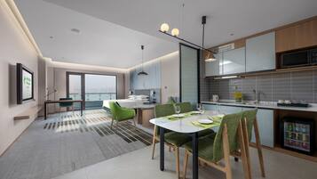 Quarto de hotel moderno com área de refeições, cozinha e vista para a cidade.