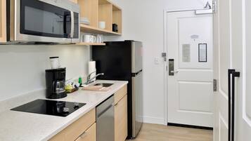Uma cozinha compacta equipada com micro-ondas, máquina de café e lava-louças.