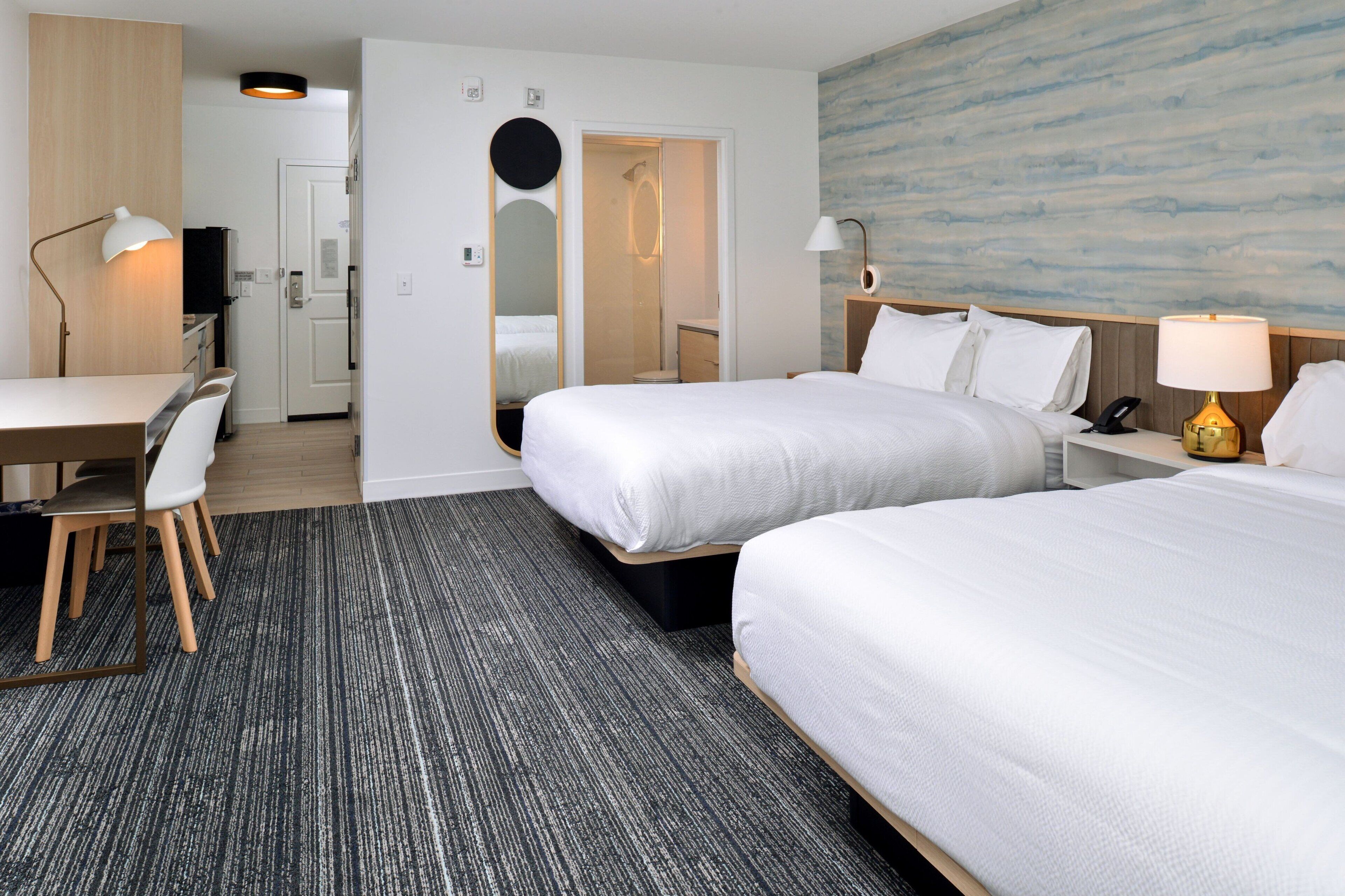 Une chambre d’hôtel avec deux lits, un bureau et une chaise.
