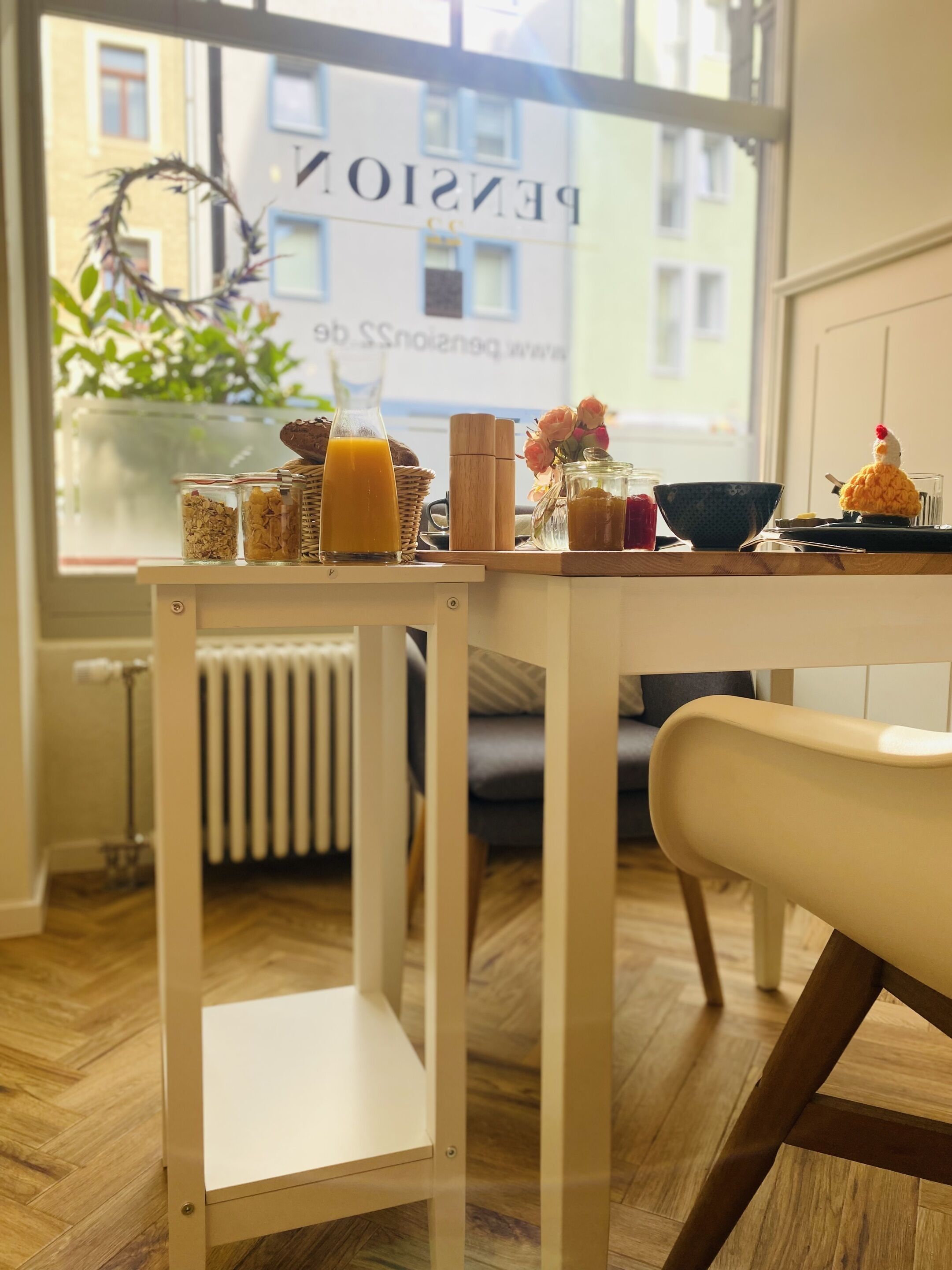 A breakfast table with a variety of food items and a view of a building with the sign "Pension 55".