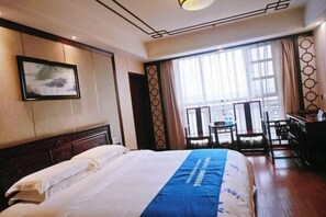 Ein Hotelzimmer mit Bett, Schreibtisch und Stuhl in der Nähe eines Fensters.