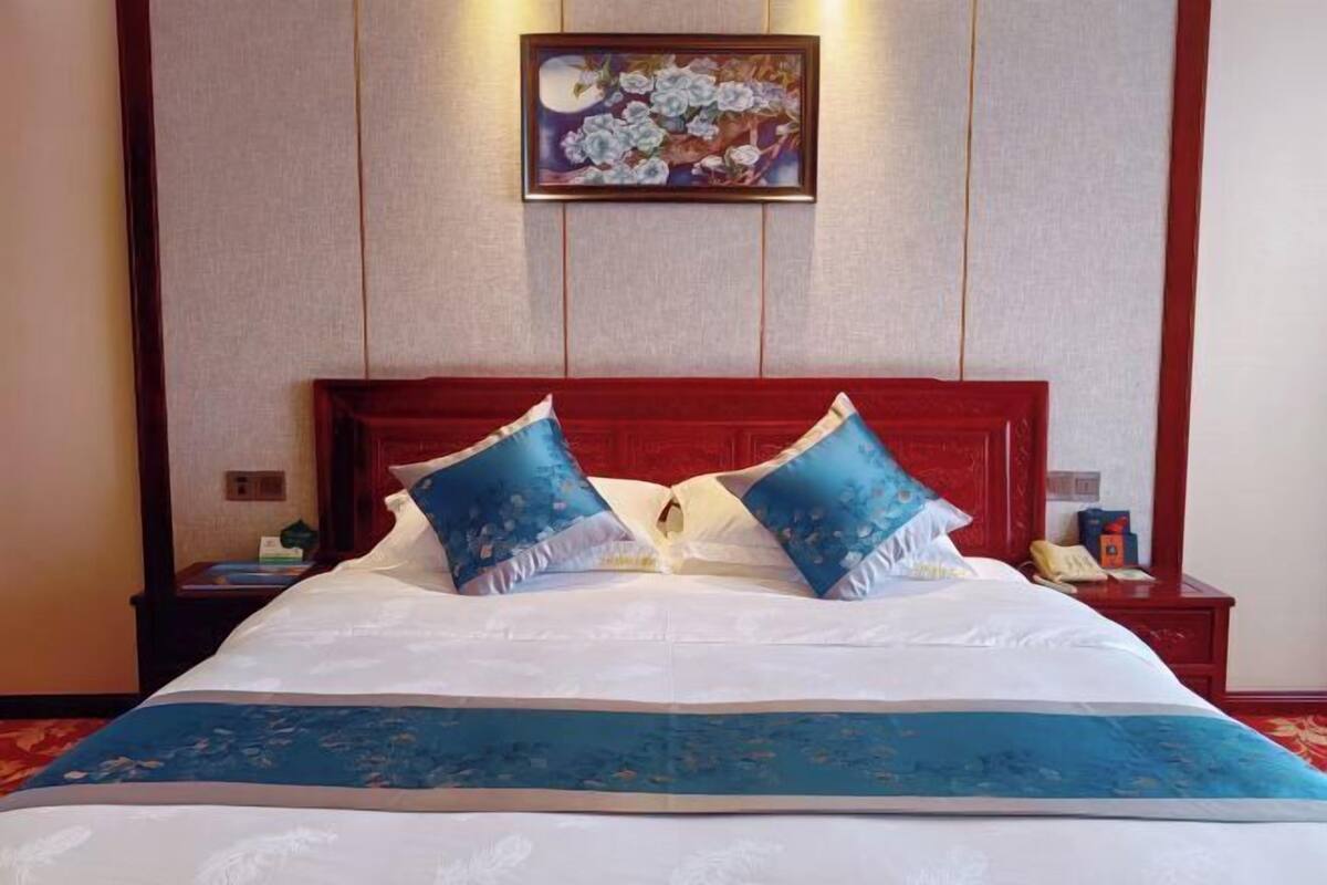 A neatly made bed with a blue and white bedspread, two matching pillows, and a red headboard.