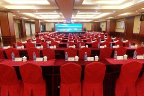 Un salón de conferencias con filas de mesas y sillas, tarjetas de identificación y botellas de agua.