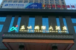A hotel with a prominent sign for Yuxia International Hotel. - Yuxia International Hotel (Xiajiang)