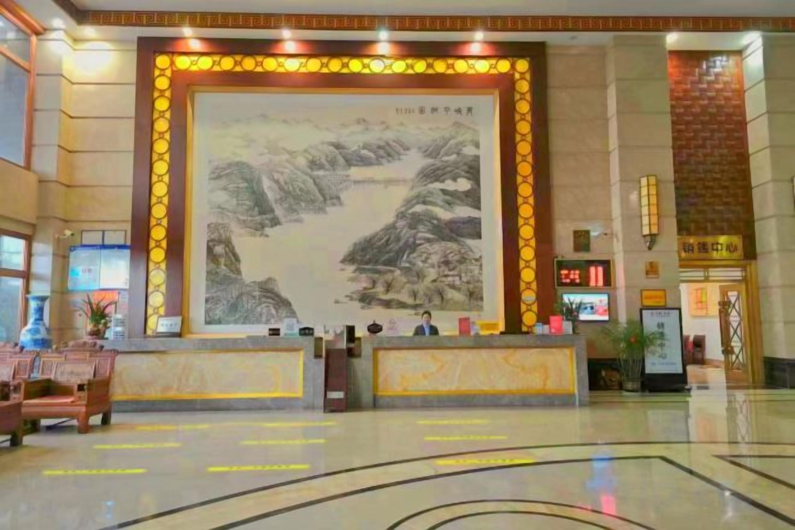 A hotel lobby with a reception desk, a large mural, and a modern floor design.