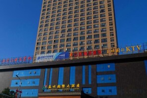 Een hoog gebouw met meerdere verdiepingen, grote ramen en een opvallend bord met Chinese karakters.