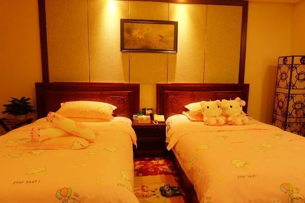 Una habitación de hotel con dos camas, cada una con un peluche y una almohada.