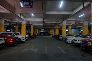 A multi-level parking garage with cars parked in rows, directional arrows on the floor, and a sign indicating the exit. - Yuxia International Hotel (Xiajiang)